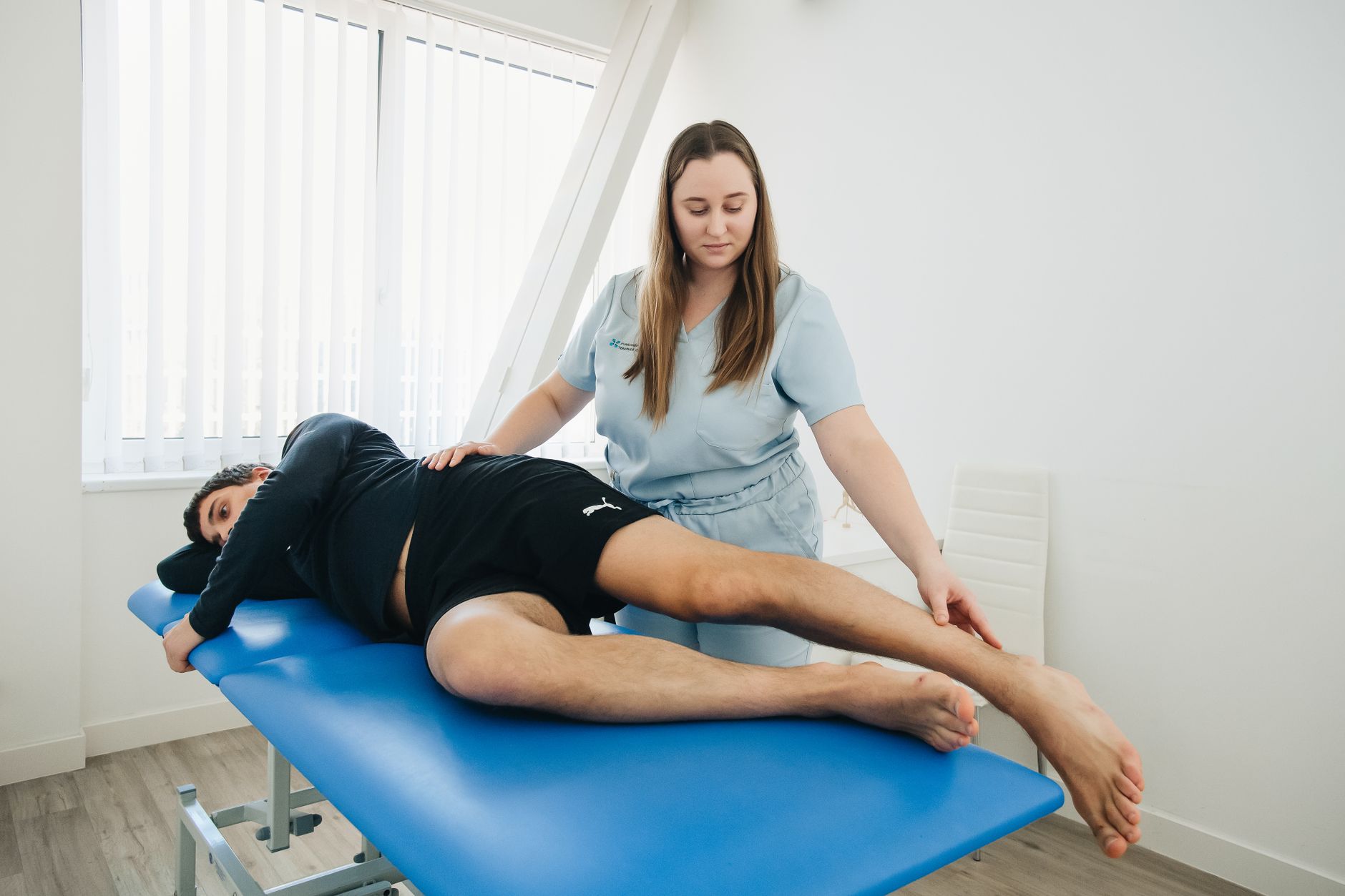 Różnice między osteopatią a fizjoterapeutyczną terapią manualną: w czym się uzupełniają a gdzie podejście jest odmienne Fizjoterapeuta pomaga pacjentowi podczas rehabilitacji w klinice