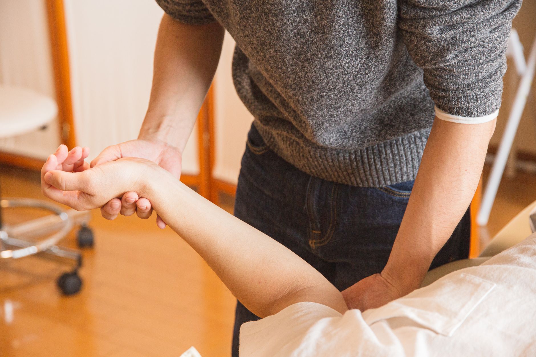 Terapeuta masuje kontuzjowany nadgarstek pacjenta podczas rehabilitacji