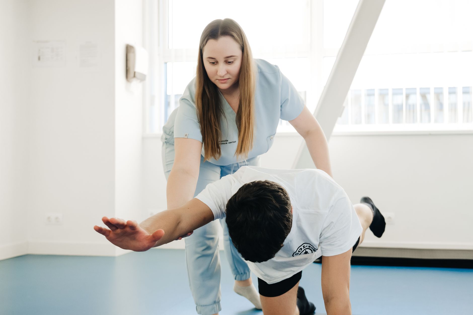 Fizjoterapeuta pomaga pacjentowi w ćwiczeniach rozciągających indoors