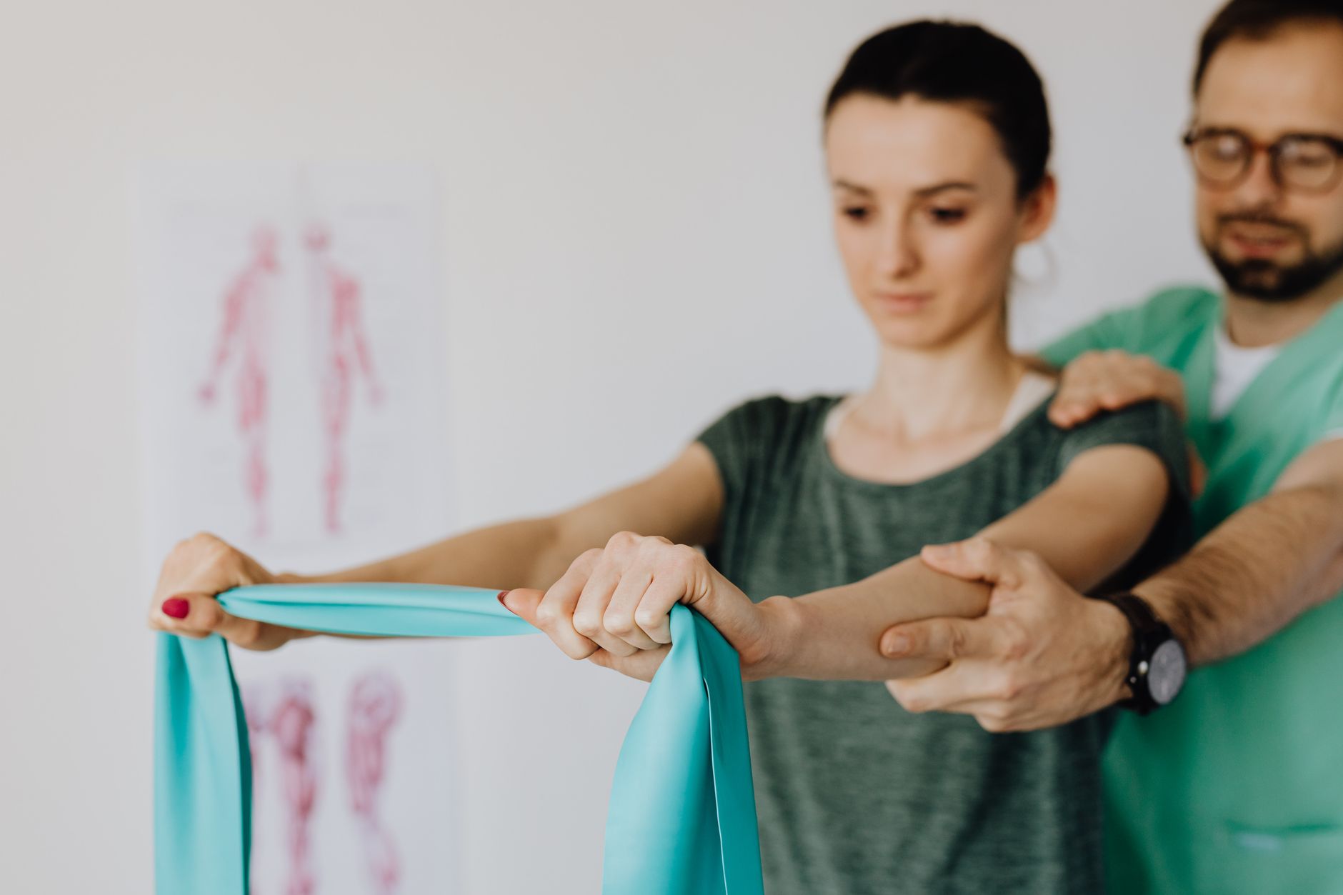 Terapeuta wspiera ramię młodej kobiety z taśmą elastyczną